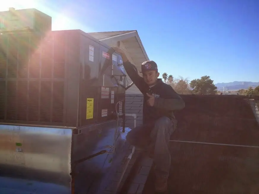 HVAC technician performing AC Tune-Up on a rooftop unit in Two Rivers